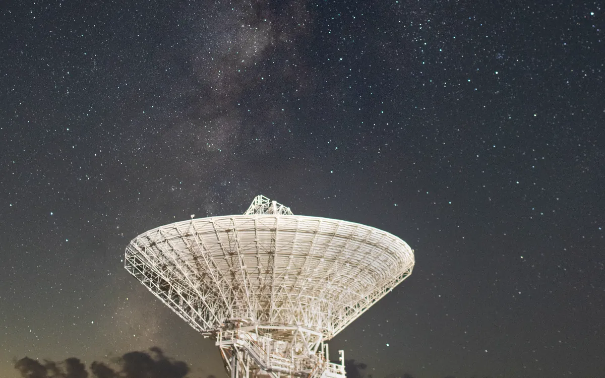 34-metrowa antena Deep Space Network DSS-15 w Goldstone wycelowana w nocne niebo, nad nią pas Drogi Mlecznej