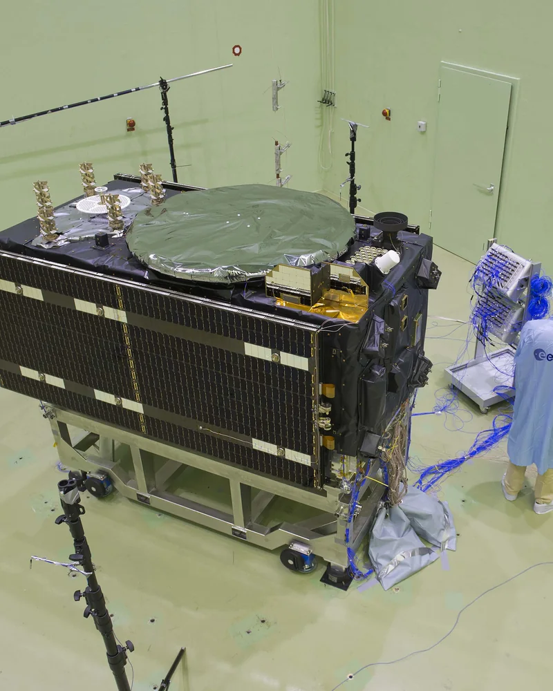 Satelita Galileo w hali testowej, wokół mikrofony i technicy w kombinezonach