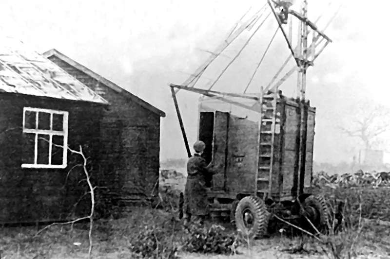 Czarno-białe zdjęcie z 1945 roku: drewniany barak i wojskowy radar na przyczepie kołowej w Jodrell Bank