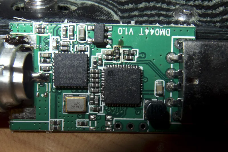 Rozebrany odbiornik SDR na USB: zielona płytka z układami scalonymi obok złącza antenowego