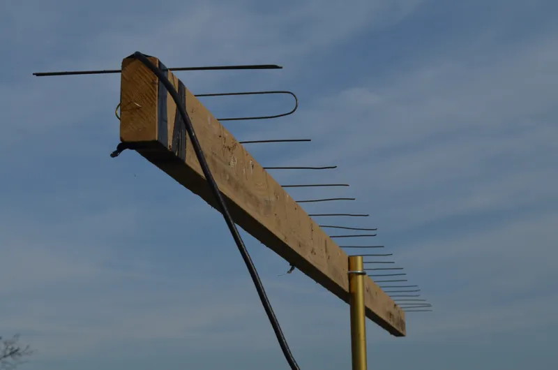 Domowa antena Yagi z drutu na drewnianej belce, na końcu dipol pętlowy, w tle niebo