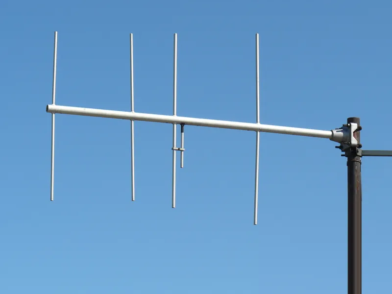 Czteroelementowa antena Yagi z pionowymi elementami na tle błękitnego nieba, belka zamocowana końcem do masztu